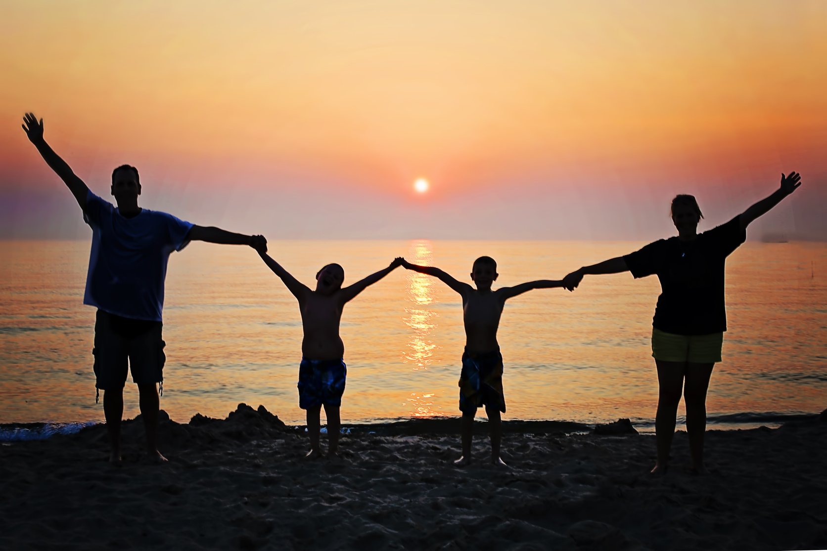 Silhouette of a Family by the Sea at Sunset